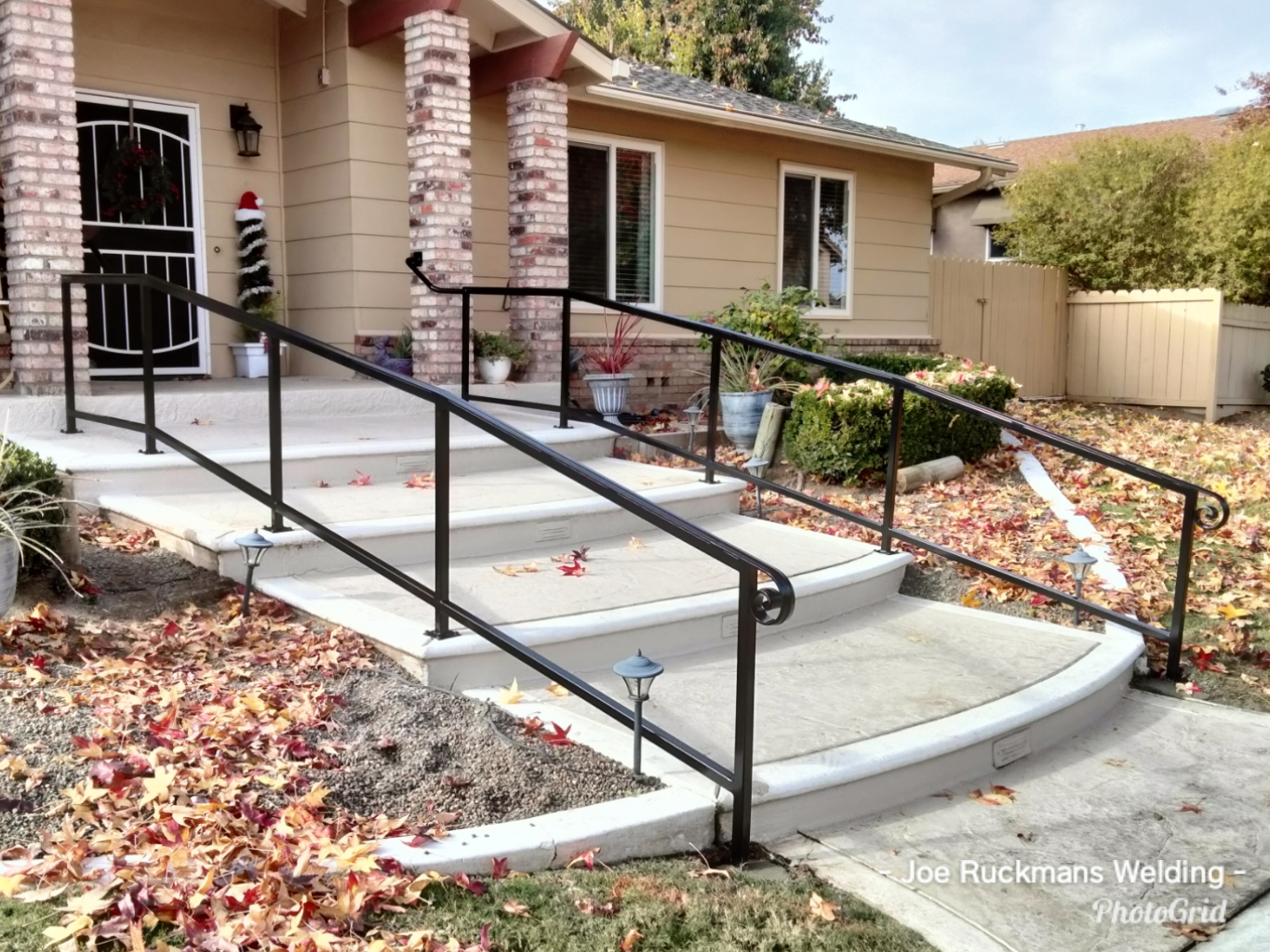 Custom black steel handrails installed along a curved front walkway and steps